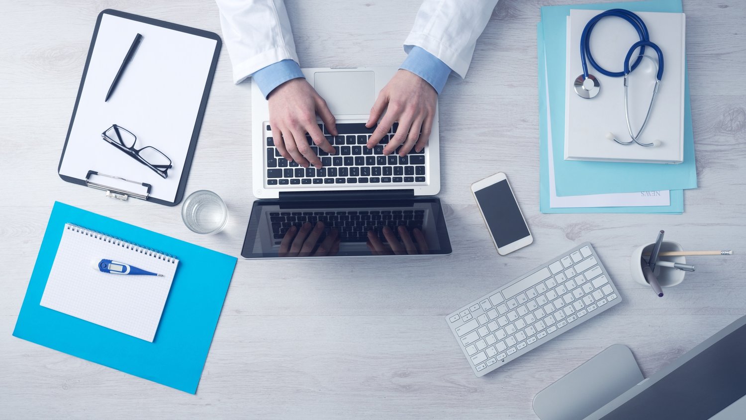 A laptop is being used on a desk covered in medical instruments